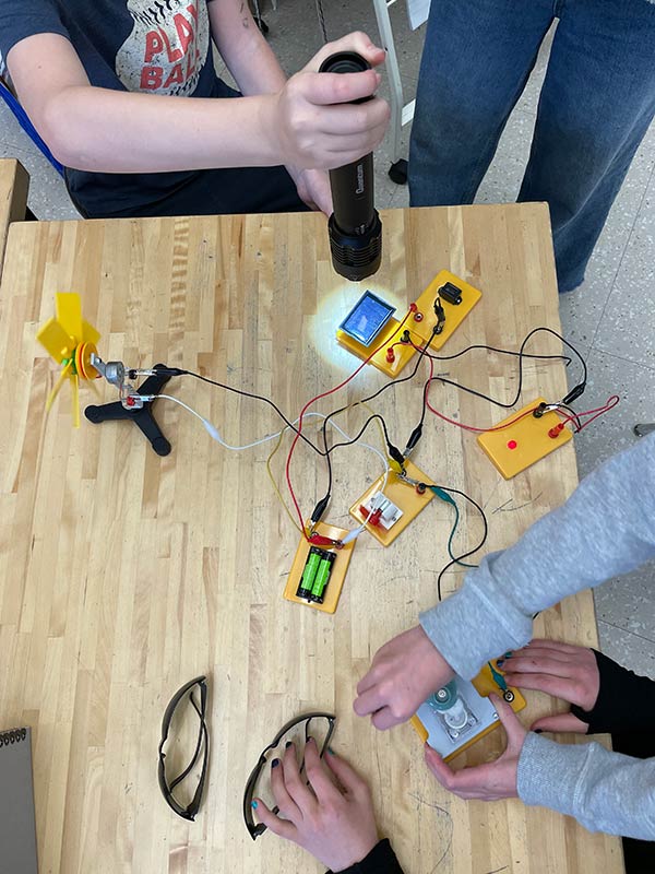 Students use their own flashlights to power solar panels